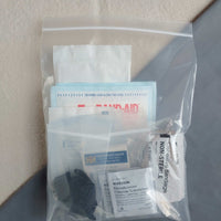 First aid kit pouch containing gauze pads latex gloves compressed gauze bzk wipes eye pad and cohesive bandage in baggie