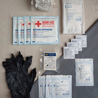 First aid kit pouch containing gauze pads latex gloves compressed gauze bzk wipes eye pad and cohesive bandage